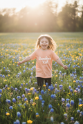 Child wearing Sunshine Kid tee running through spring meadow